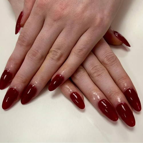 Close-up of hands with dark red nail polish on a light background