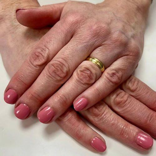 Hands with painted pink nails on a light background 