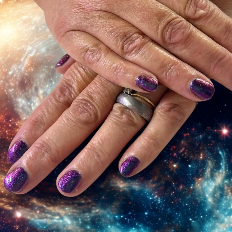 A close-up of two hands with glittery purple nail polish, one wearing a silver ring, set against a vibrant galaxy space background.