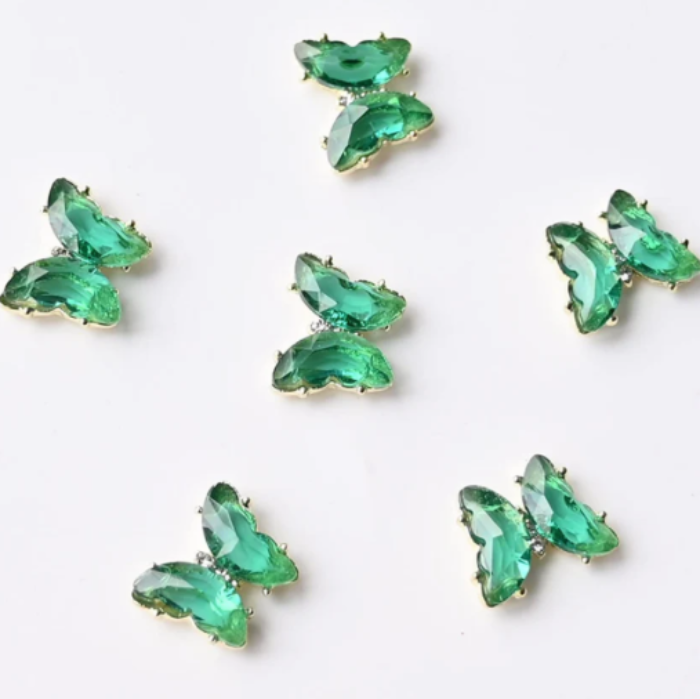 Green butterfly-shaped nail gems on a white background