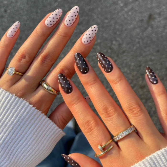 Close-up of hands with polka dot nail design and multiple rings.