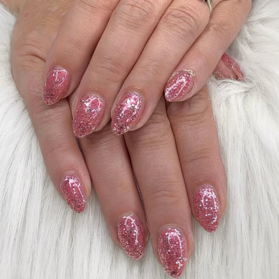 Close-up of hands with pink glittery nail polish on a white background