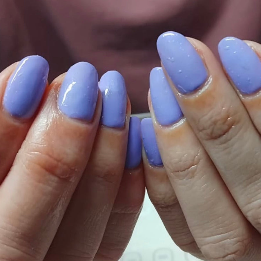 Close up of hands showing painted nails in a purply-blue colour 