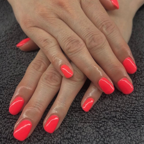 Close-up of hands with bright red nail polish on a dark textured background