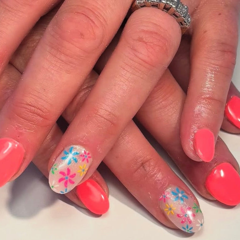 Close-up of hands with pink nail polish and floral designs on a light background