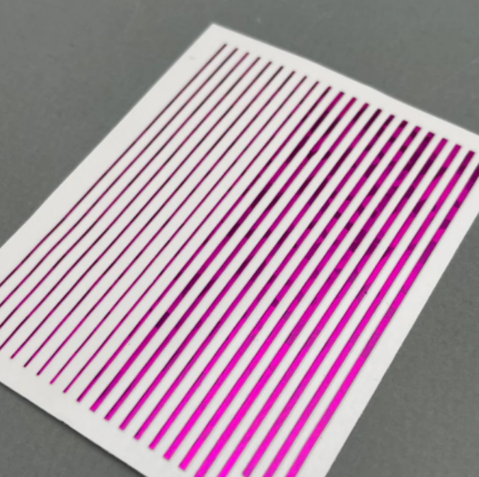 Sheet of magenta nail art metallic stripes on a grey background