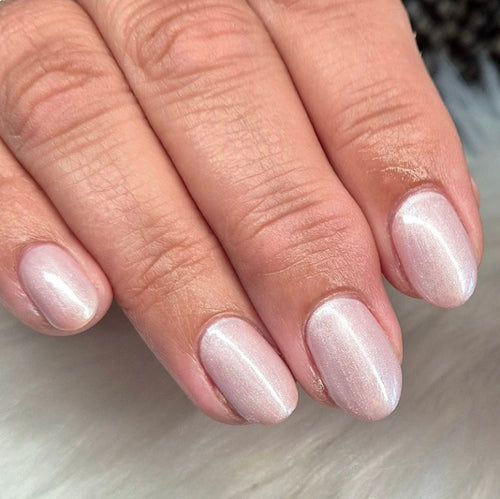 Close-up of a hand with light pink nail polish on a neutral background