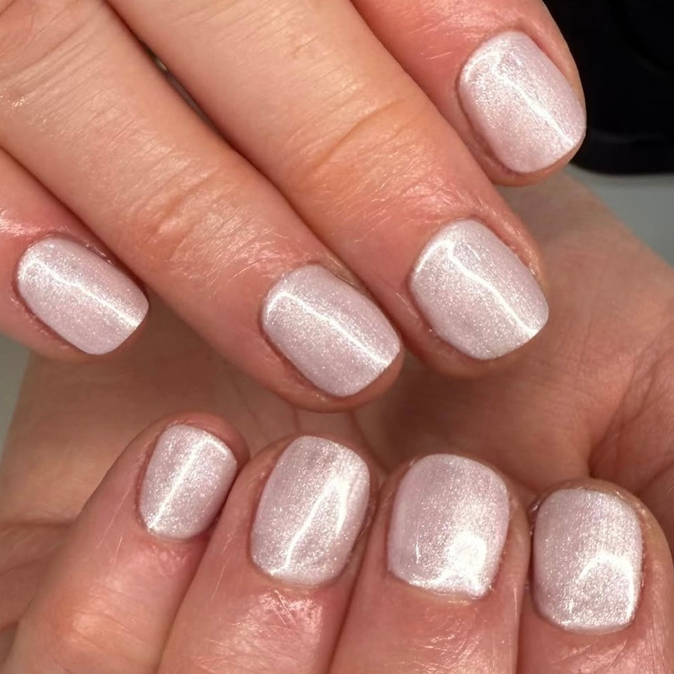 Close-up of a hand with silver glittery nail polish on a neutral background