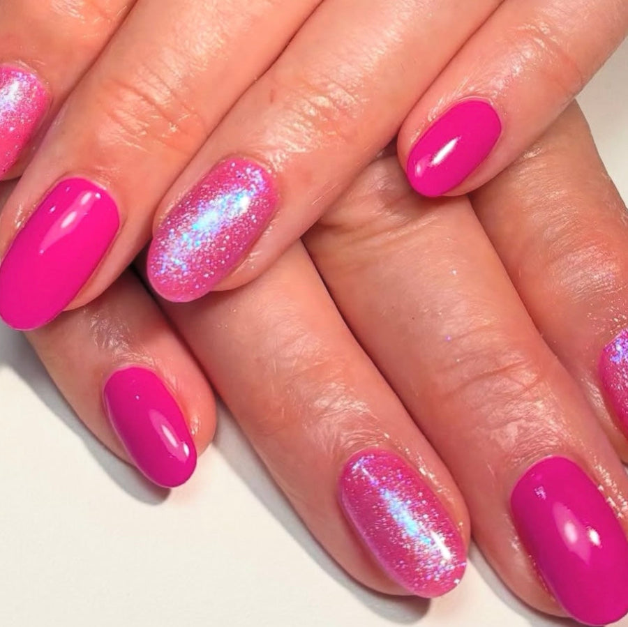 Close-up of hands with pink glittery nail polish on a neutral background