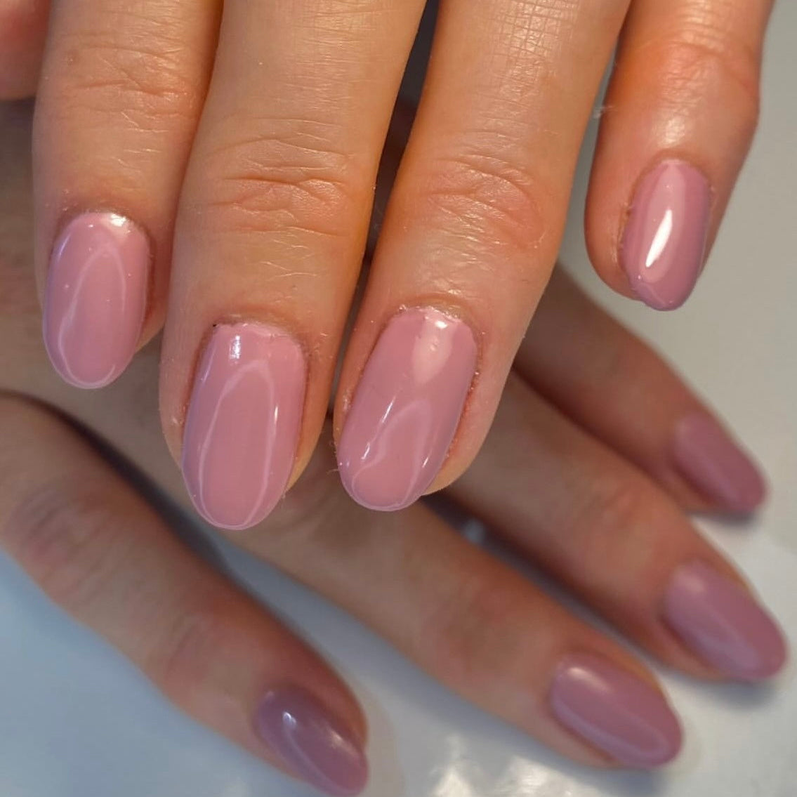 Hands with pink nails on a light background