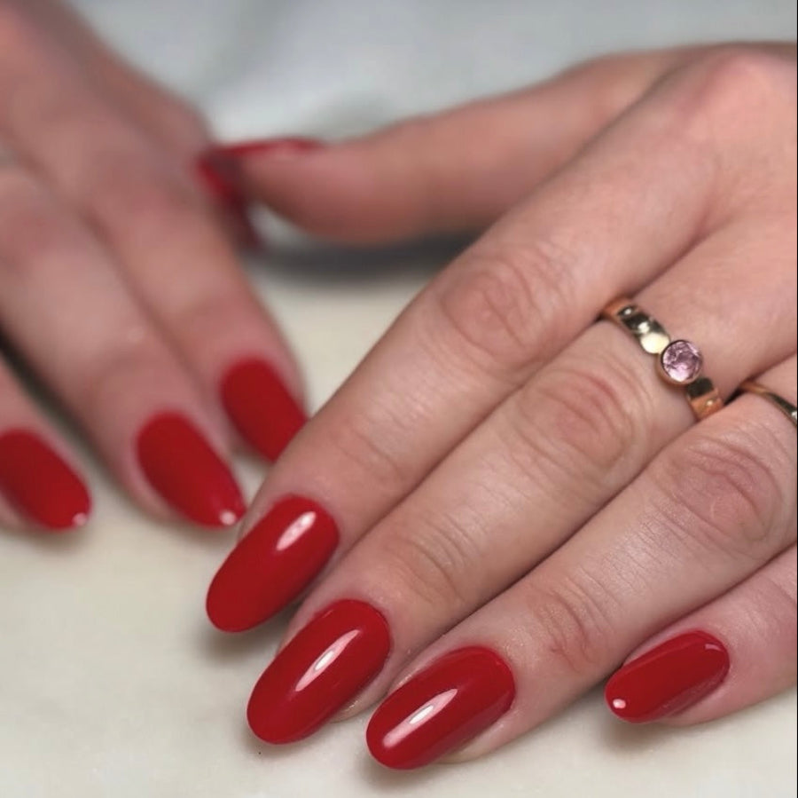 Close-up of hands with red nail polish on a neutral background