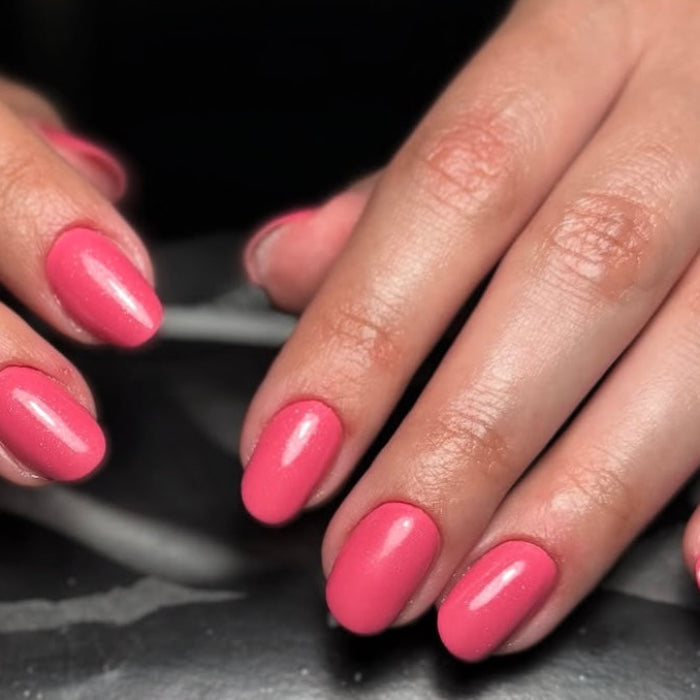Close-up of hands with pink nail polish on a dark background