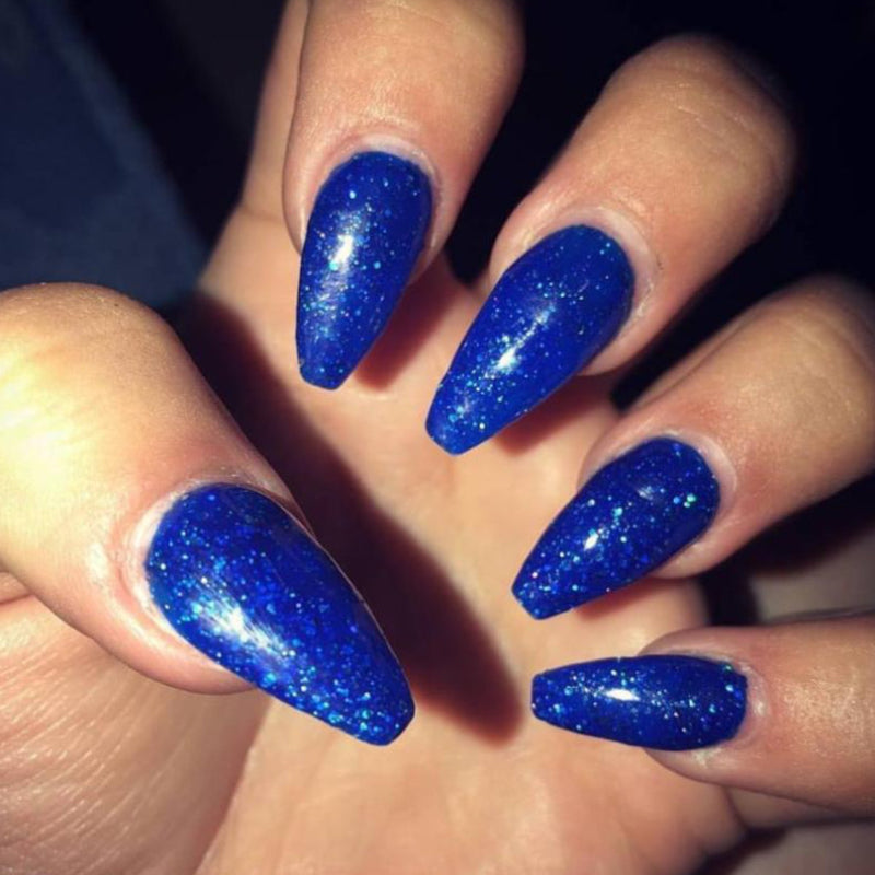 Close-up of a hand with blue glittery nail polish on a dark background